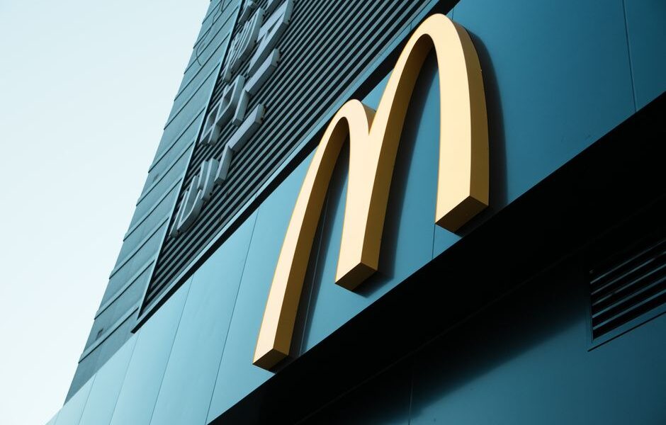 Złote logo McDonald's na ciemnej ścianie budynku widziane z dołu