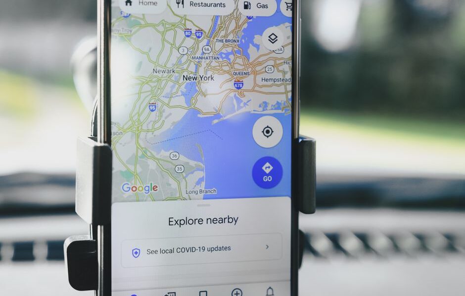 Smartfon w uchwycie samochodowym z otwartą aplikacją Google Maps