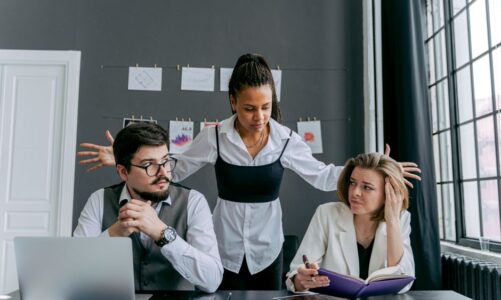 Trójka współpracowników przy biurku z laptopem i notatnikiem w biurze